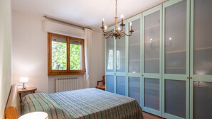 A bedroom with a bed, a window, a chandelier, and a wardrobe. - Apartment 'Casa Levanella' with Private Garden (Montevarchi)