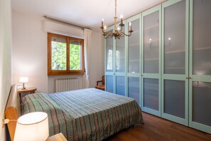 Ein Schlafzimmer mit Bett, Fenster, einer Kronleuchter und einem Kleiderschrank.