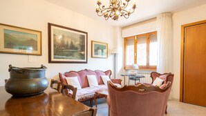 A room with a wooden table, a sofa, a chandelier, and framed pictures on the wall. - Apartment 'Casa Levanella' with Private Garden (Montevarchi)