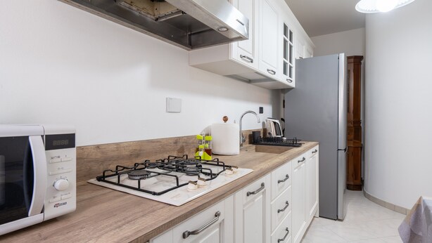 A kitchen with a gas stove, microwave, white cabinets, and a stainless steel refrigerator. - Apartment 'Casa Levanella' with Private Garden (Montevarchi)