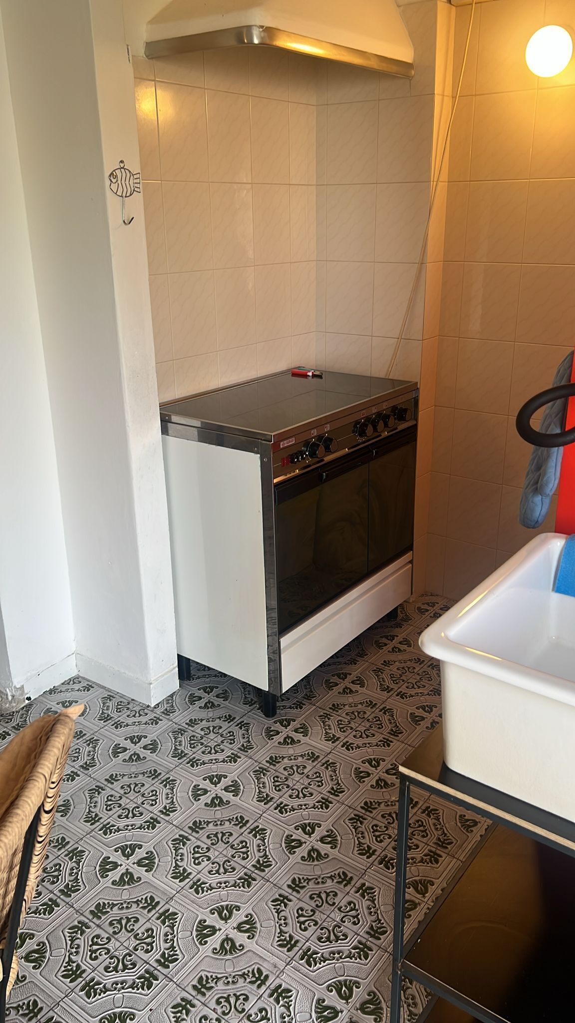 Una cocina con estufa, horno y suelo de baldosas estampadas.