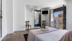 Une chambre avec un lit, une chaise, une télévision et un balcon donnant sur une vue agréable.