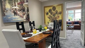 A dining area with a wooden table, chairs, and a painting on the wall. - House Sleeps 6 With Garden and Parking (Leeds)