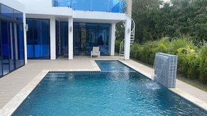 Ein modernes Gebäude mit Pool, überdachter Terrasse und Blick ins grüne Umland.