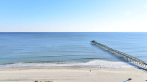 A beach with a long pier extending into the ocean.