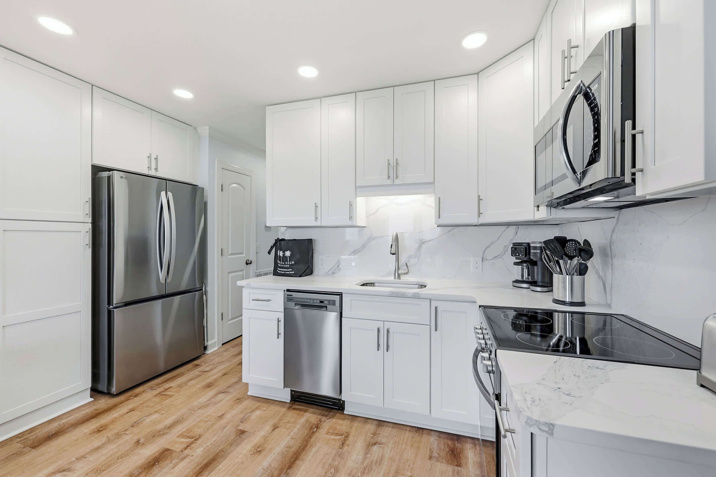 Una cocina moderna con armarios blancos, electrodomésticos de acero inoxidable, lavavajillas y microondas.