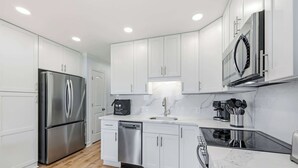 A modern kitchen with white cabinets, stainless steel appliances, a dishwasher, and a microwave.