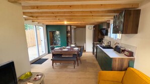 A modern kitchen with wooden beams, a dining area with a table set for four, and a yellow sofa. - Ty Argoat -  Your haven between land and sea (Plouarzel)