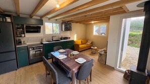 A modern kitchen with wooden beams, a dining table set for four, a sofa, and a large window. - Ty Argoat -  Your haven between land and sea (Plouarzel)