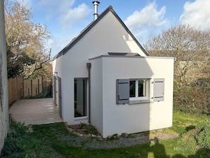 Een modern huis met een schuin dak, schoorsteen en een klein bijgebouw met een raam.
