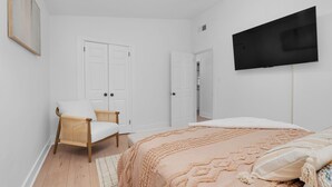 Ein Schlafzimmer mit einem Bett, einem Sessel, einem Fernseher und zwei Türen.