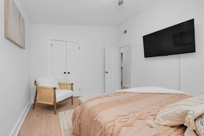 Ein Schlafzimmer mit einem Bett, einem Sessel, einem Fernseher und zwei Türen.