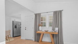 Eine moderne Küche mit einem eingebauten Kühlschrank, einem Holztisch und einem Fenster mit grauen Vorhängen.