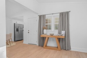 Eine moderne Küche mit einem eingebauten Kühlschrank, einem Holztisch und einem Fenster mit grauen Vorhängen.