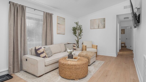 Ein Wohnzimmer mit Sofa, Sessel und Couchtisch, einem Deckenventilator und einem Flur, der in einen anderen Raum führt.