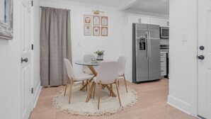 Eine moderne Küche mit einem Edelstahl-Kühlschrank, einem Esstisch mit Stühlen und einem kleinen Teppich.