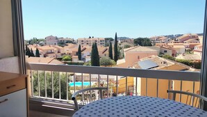 A balcony with a table and chairs, overlooking a residential area with houses and trees. - 40m² AC Studio with Balcony & Parking (Sanary-sur-Mer)