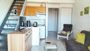 A modern apartment with a kitchen, dining area, and living room. - 40m² AC Studio with Balcony & Parking (Sanary-sur-Mer)