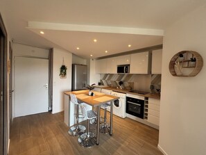 Eine moderne Küche mit einer zentralen Kochinsel, Edelstahlgeräten und einer Küchenwand mit Fischgrätmusterfliesen.