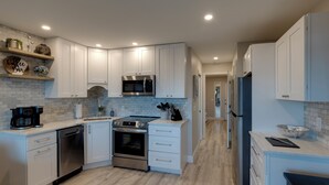 Een moderne keuken met witte kastjes, roestvrijstalen apparatuur en een houten aanrecht.