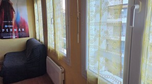 Ein Zimmer mit einem Poster, einem Heizkörper, einem Fenster mit Vorhängen und einer Tür.