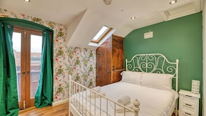 Un dormitorio con cama, tragaluz, armario de madera y pared verde.