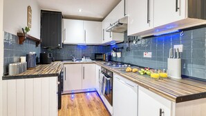 Una cocina moderna con armarios blancos, encimera de madera e iluminación LED azul.