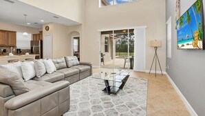A spacious living room with a large sectional sofa, a glass coffee table, and a patterned rug. - Spacious Family Home w Pool, Hot Tub & BBQ (Kissimmee)