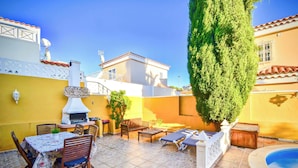 A patio with a table, chairs, a barbecue grill, lounge chairs, and a swimming pool. - Casa Culwick - Villa in Gran Canaria with Swimming Pool (Mogán)
