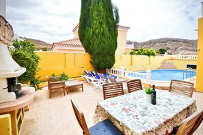 Eine Terrasse mit Pool, Sitzgelegenheiten im Freien und einem Tisch mit einer Flasche.