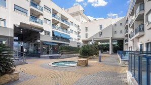 Et hotel med flere etager, med altaner, en central gårdsplads med en springvand og en overdækket indgang.