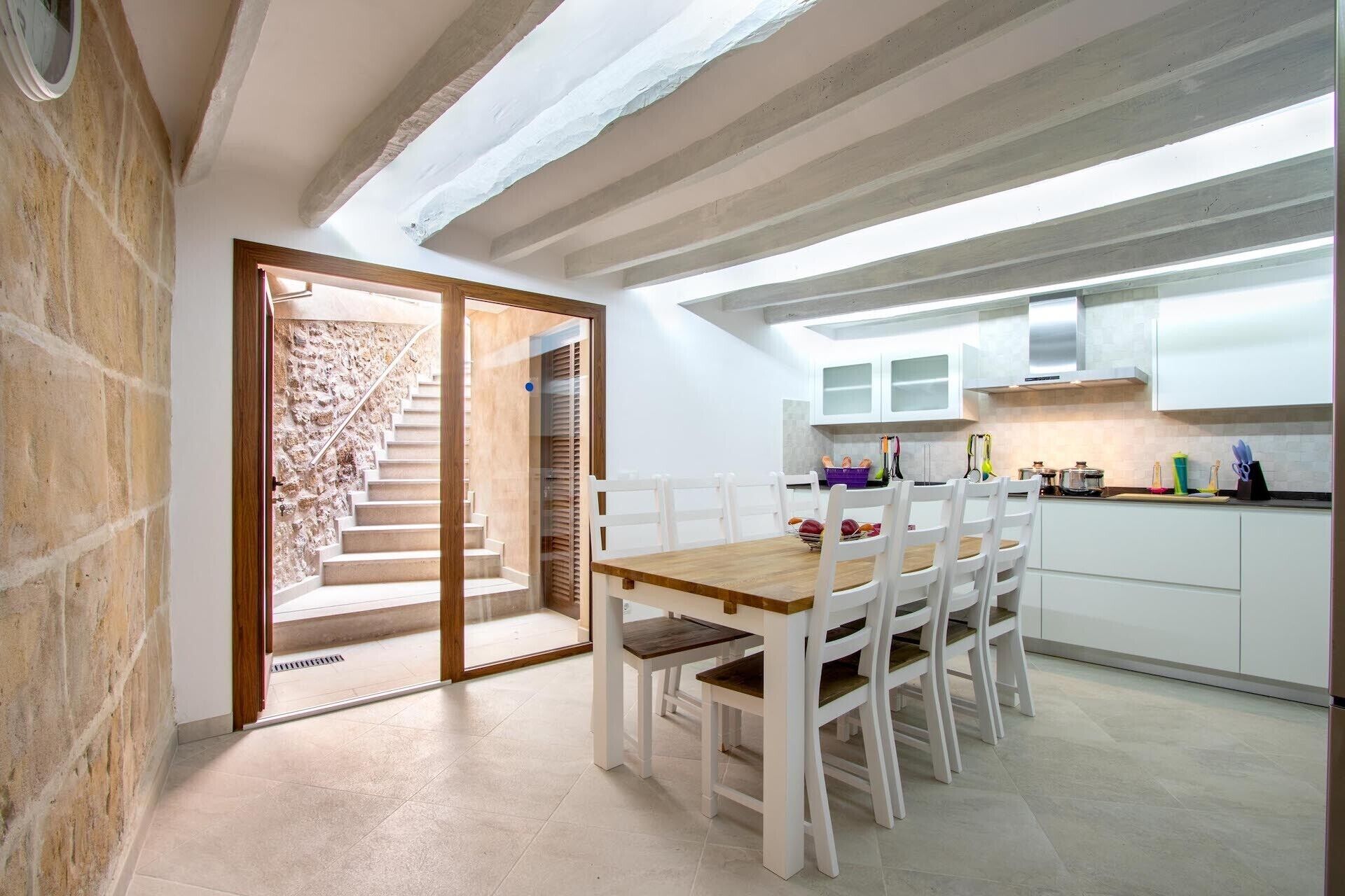 A modern kitchen with white cabinets and a wooden dining table.