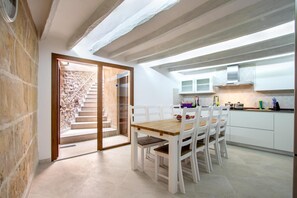 A modern kitchen with white cabinets and a wooden dining table. - Holiday Home "Horta 55" with Pool, Wi-Fi, Air Conditioning, Garden & Terraces (Pollença)