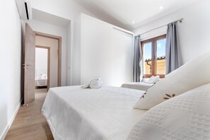 A hotel room with two beds, a bathroom visible through an open door, and a window with curtains. - Holiday Home "Horta 55" with Pool, Wi-Fi, Air Conditioning, Garden & Terraces (Pollença)