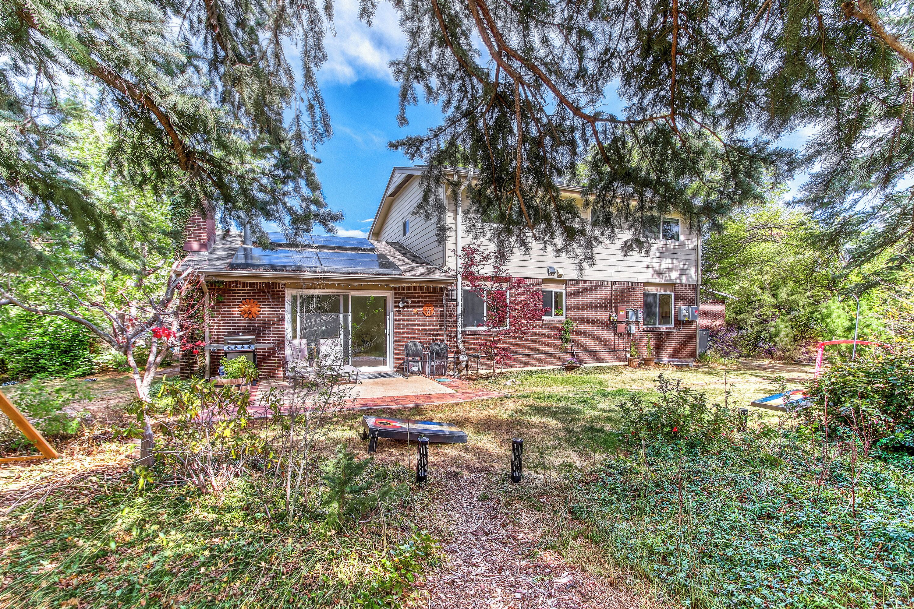A two-story house with a brick exterior, solar panels, and a well-maintained garden.