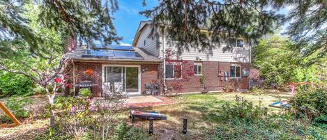 A two-story house with a brick exterior, solar panels, and a well-maintained garden.