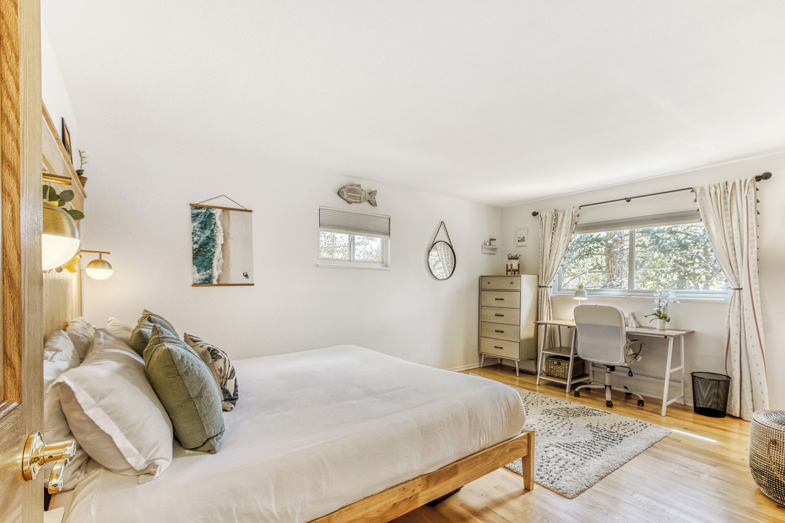 Une chambre à coucher avec un lit, un bureau, une chaise et une fenêtre avec des rideaux.