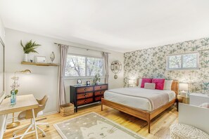 A bedroom with a bed, desk, chair, dresser, and a window.