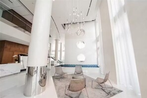 A spacious lobby with a high ceiling, modern chandeliers, and a seating area with contemporary chairs. - > Amazing NEW Remodeled LOFT < (Miami)