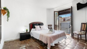 A bedroom with a bed, bedside table, chair, and a balcony view. - Casa Cubo Rural Home H12 – Authentic Charm in Alhama de Granada (Alhama de Granada)
