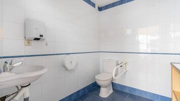 Een badkamer met witte tegels, een wastafel, een toilet en een vloer met blauwe tegels.