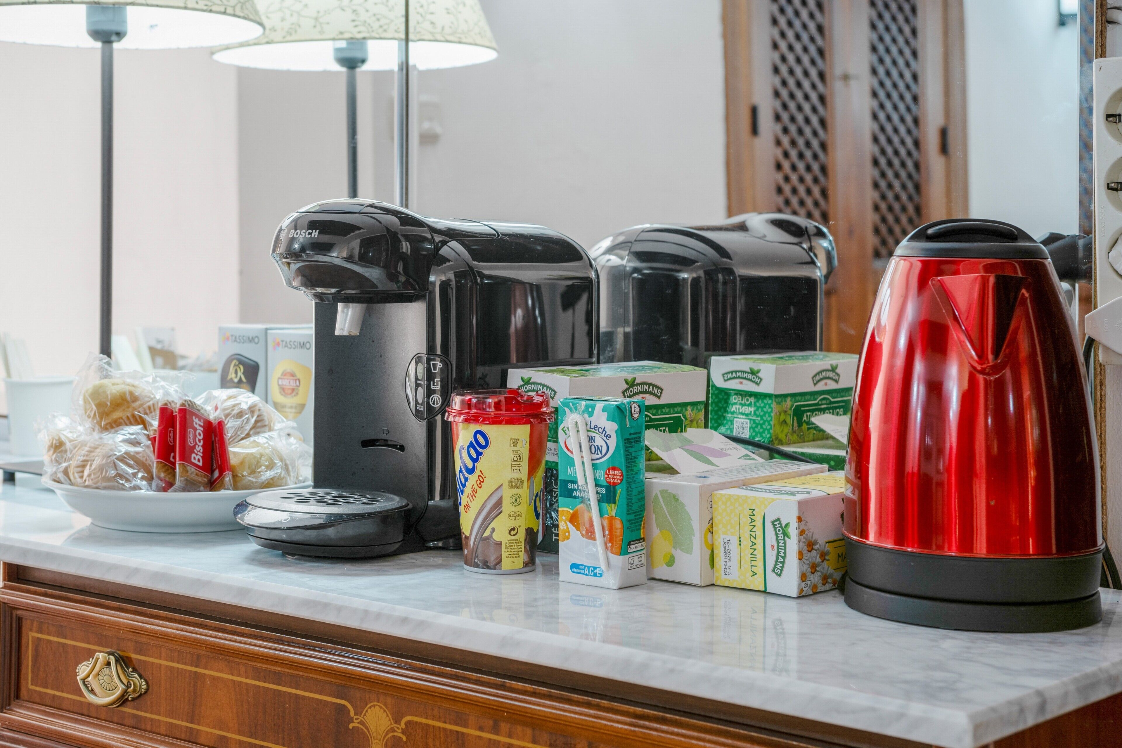 Een keukentafel met een koffiezetapparaat, broodrooster, waterkoker en diverse etenswaren.