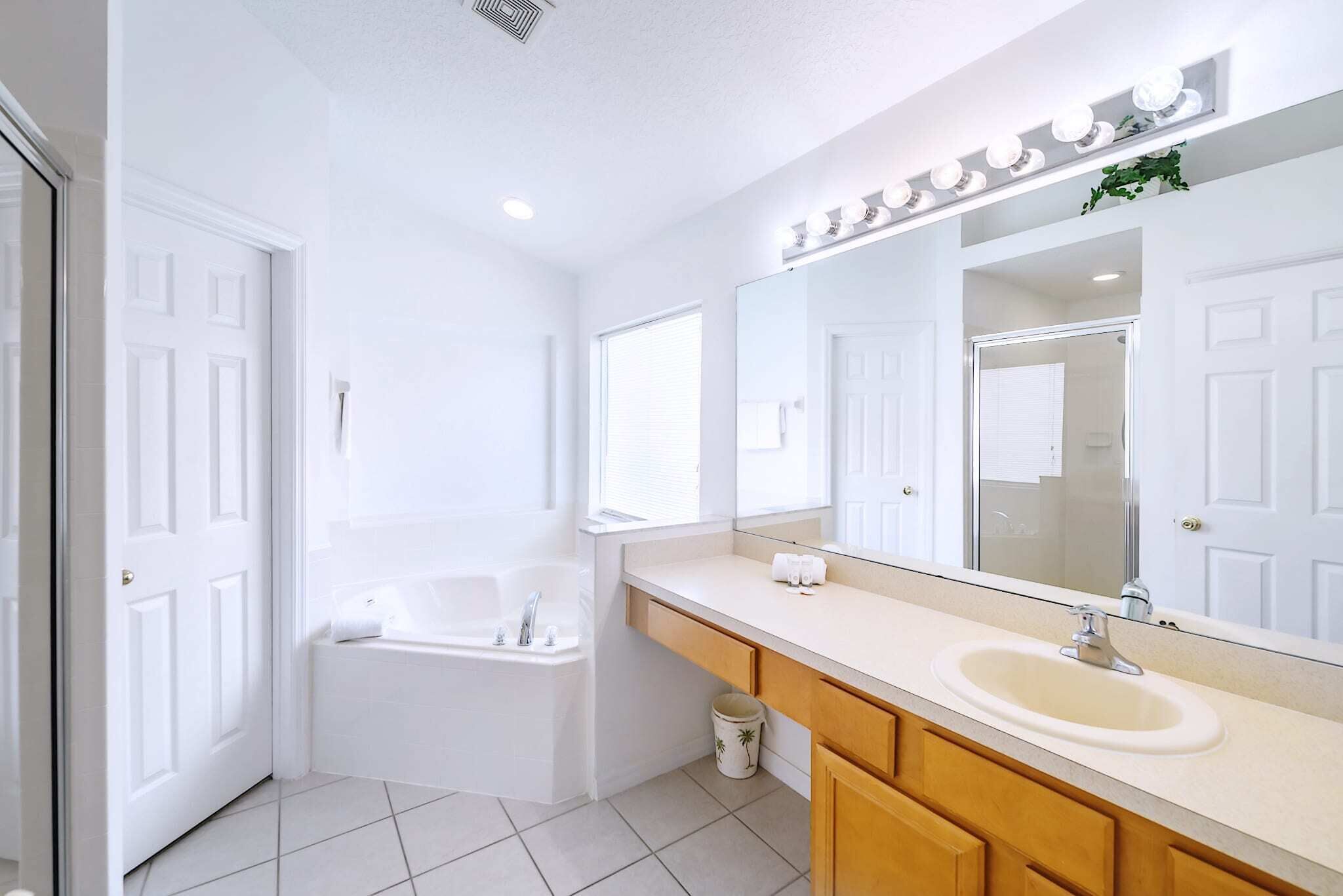 Un baño moderno con bañera, lavamanos y un espejo grande con iluminación.