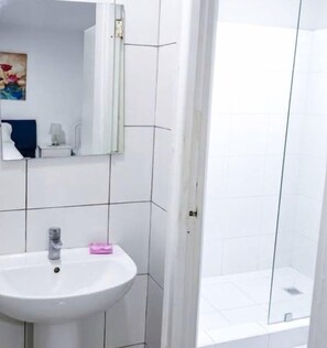 A bathroom with a white sink, a mirror, and a glass shower enclosure. - Sol Caribe Sleep&Go (Punta Cana)