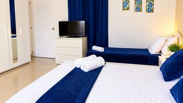 Une chambre d’hôtel avec deux lits, une télévision, une armoire et un rideau.