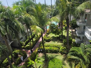 A residential area with multiple-story buildings, a pathway, and lush greenery including palm trees. - Sol Caribe Sleep&Go (Punta Cana)