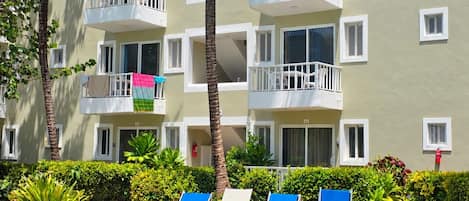 A hotel with a swimming pool, lounge chairs, and a well-maintained garden.