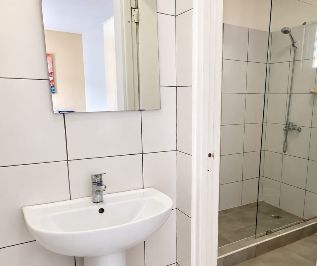 A bathroom with a white sink, a mirror, and a glass shower enclosure.