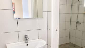 A bathroom with a white sink, a mirror, and a glass shower enclosure.