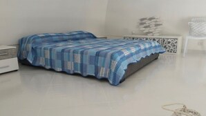 Ein Schlafzimmer mit einem Bett, einem Nachttisch, einer Lampe und einem Wanddekor.